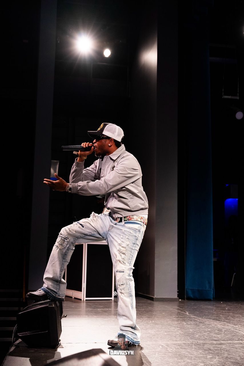 Artist performing live on stage under a spotlight