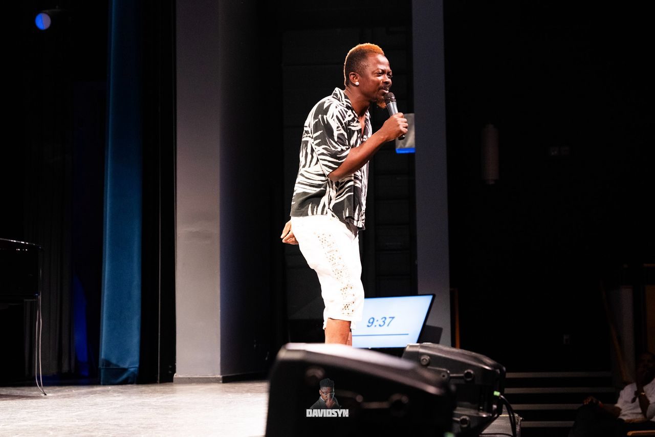 Comedian performing on a theatre stage with a handheld mic