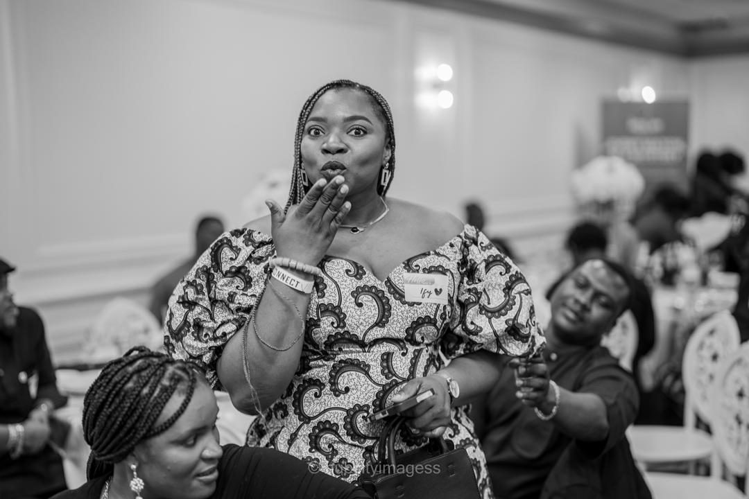 Guest in Ankara print reacting mid-conversation at a hall event