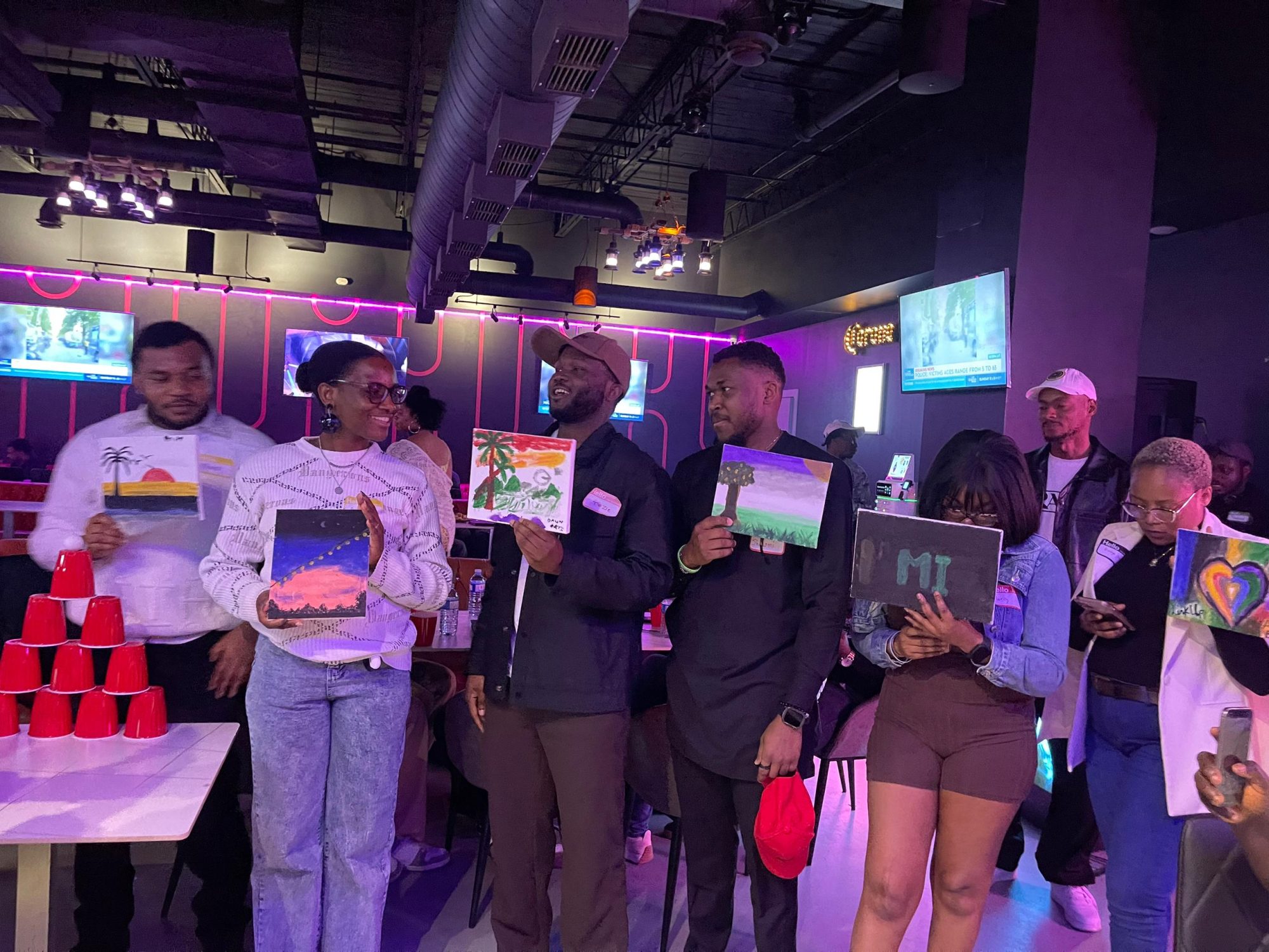 Guests showing off their paintings under neon lights