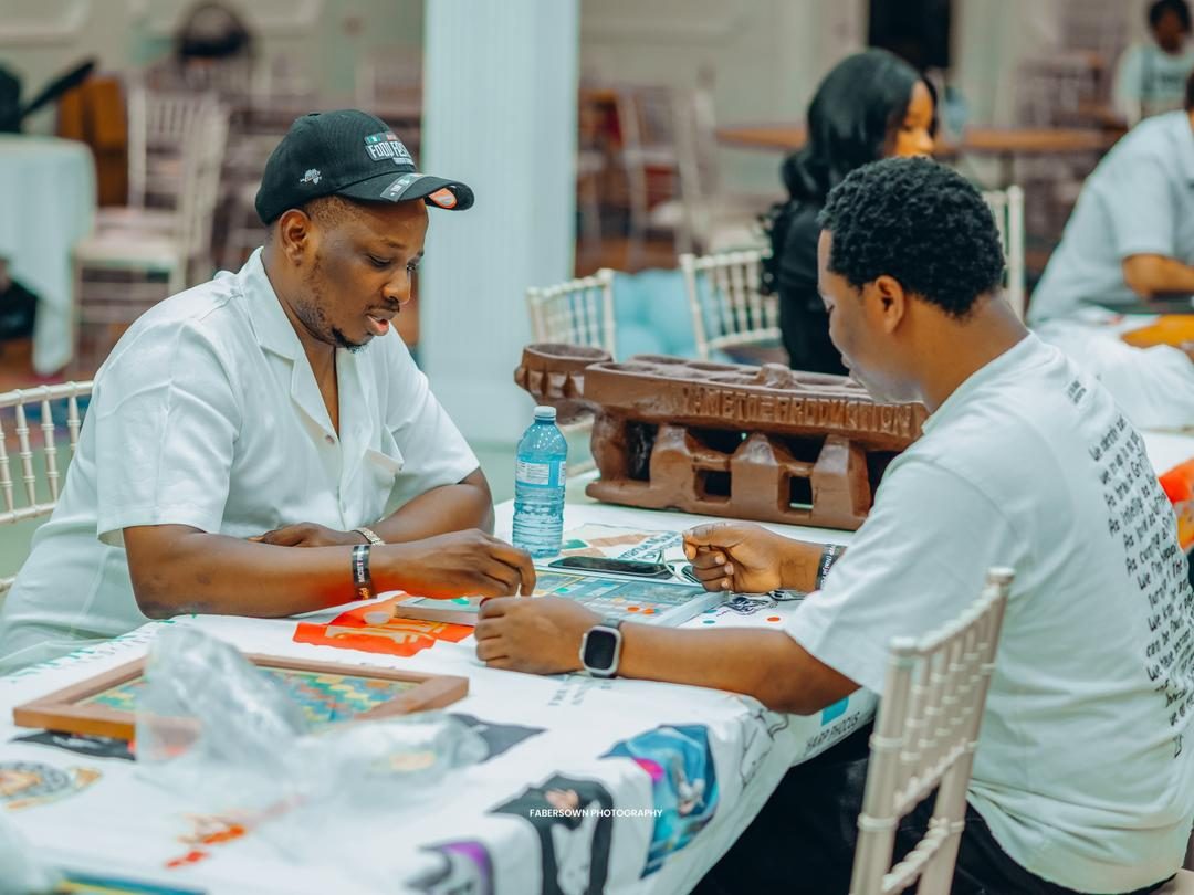Two guests playing a traditional Ayo board game at a hall event