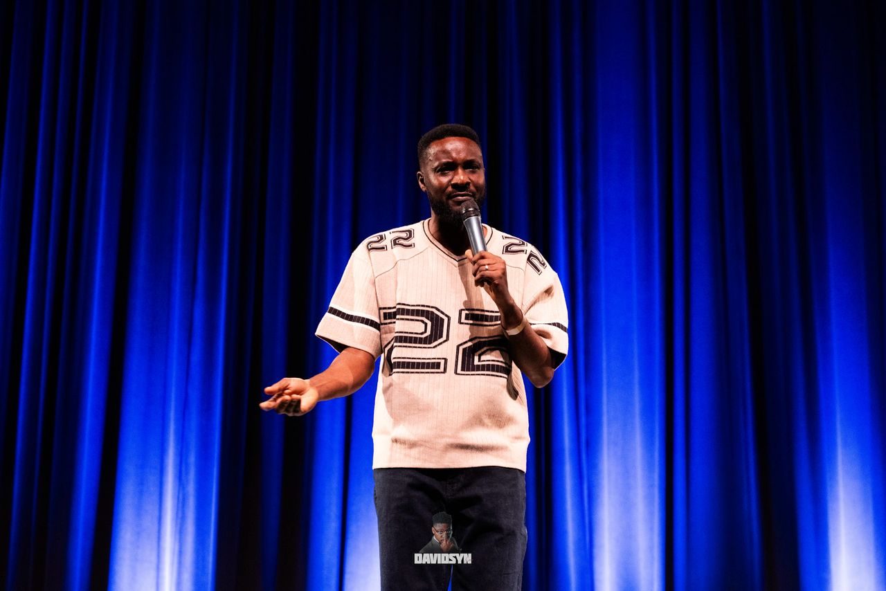 Performer on stage in front of a deep blue stage curtain