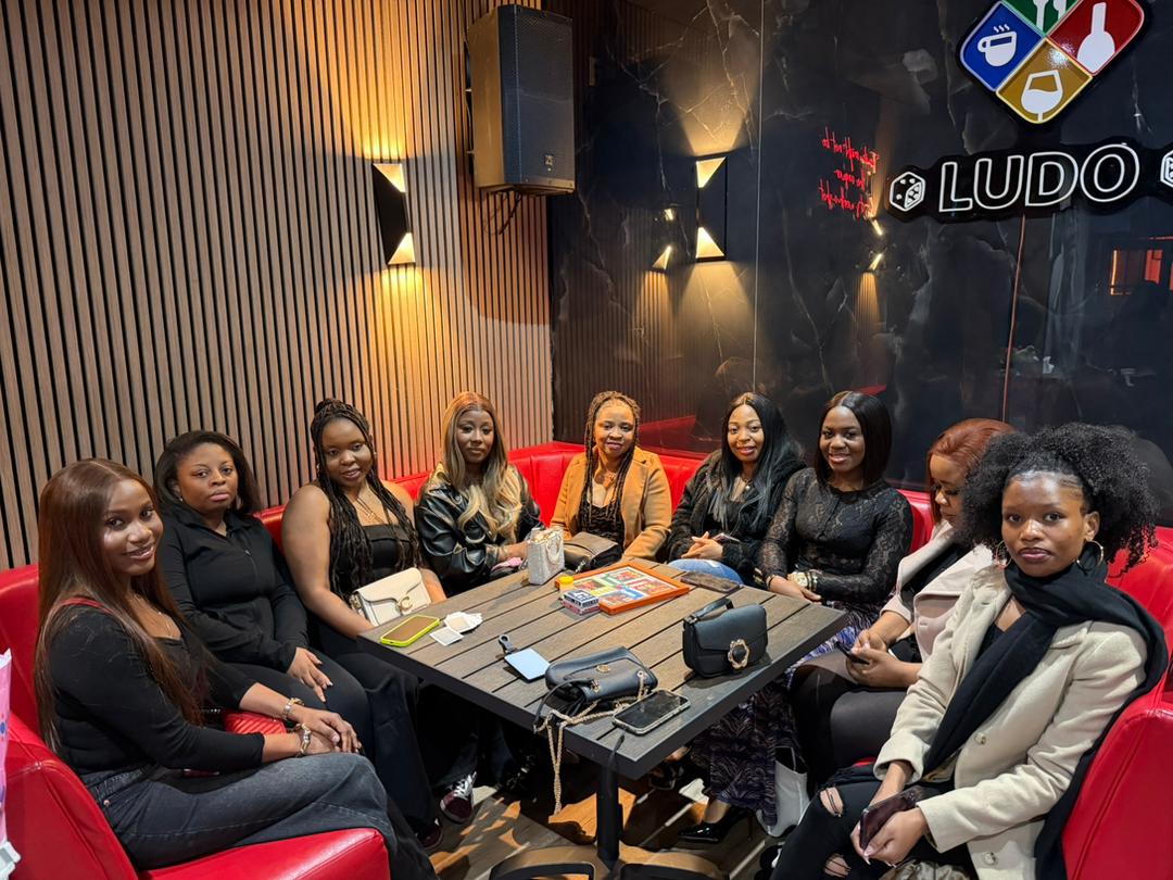 Group of friends together on red booth seating at a games night