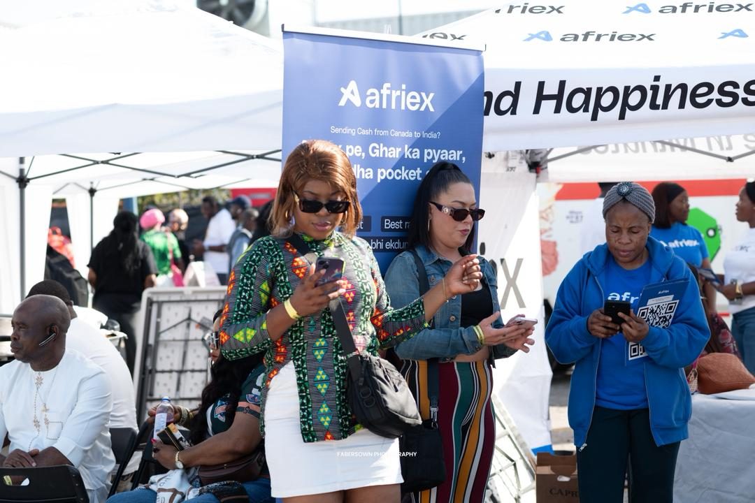 Guests in vibrant Ankara prints at an outdoor festival vendor village