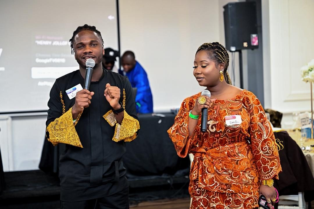 Hosts on the mic in gold-trimmed traditional outfits at a Toronto event