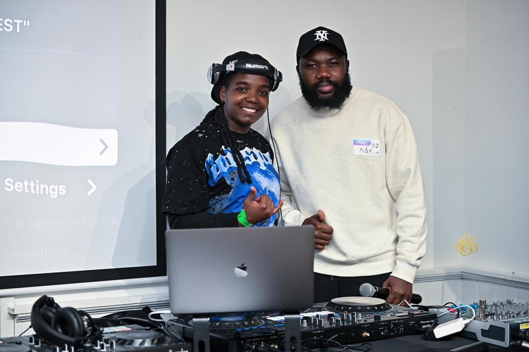 DJ duo smiling behind the decks at an indoor party