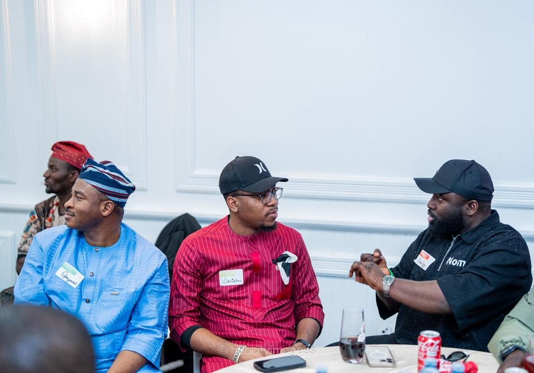 Guests in agbada and caps talking at a table